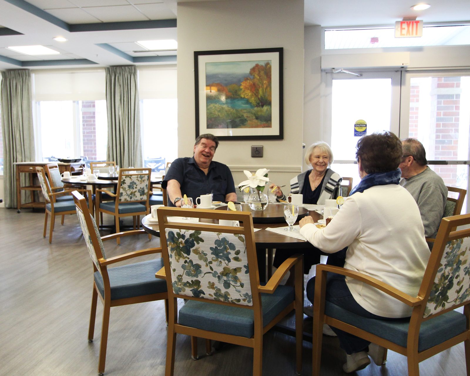 Residents laughing together over coffee in the Evolve at Lake Zurich dining room