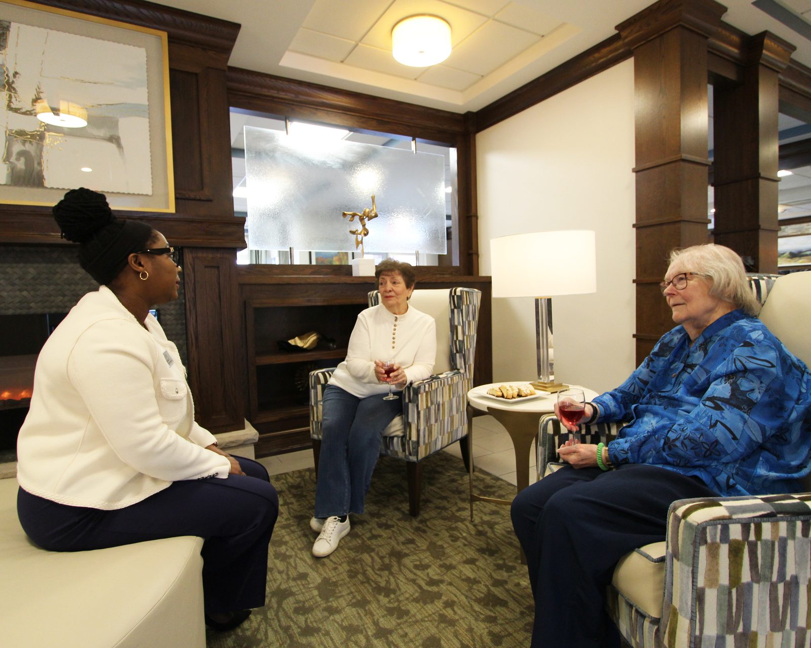 Residents and staff socializing by the fireplace at Evolve at Lake Zurich