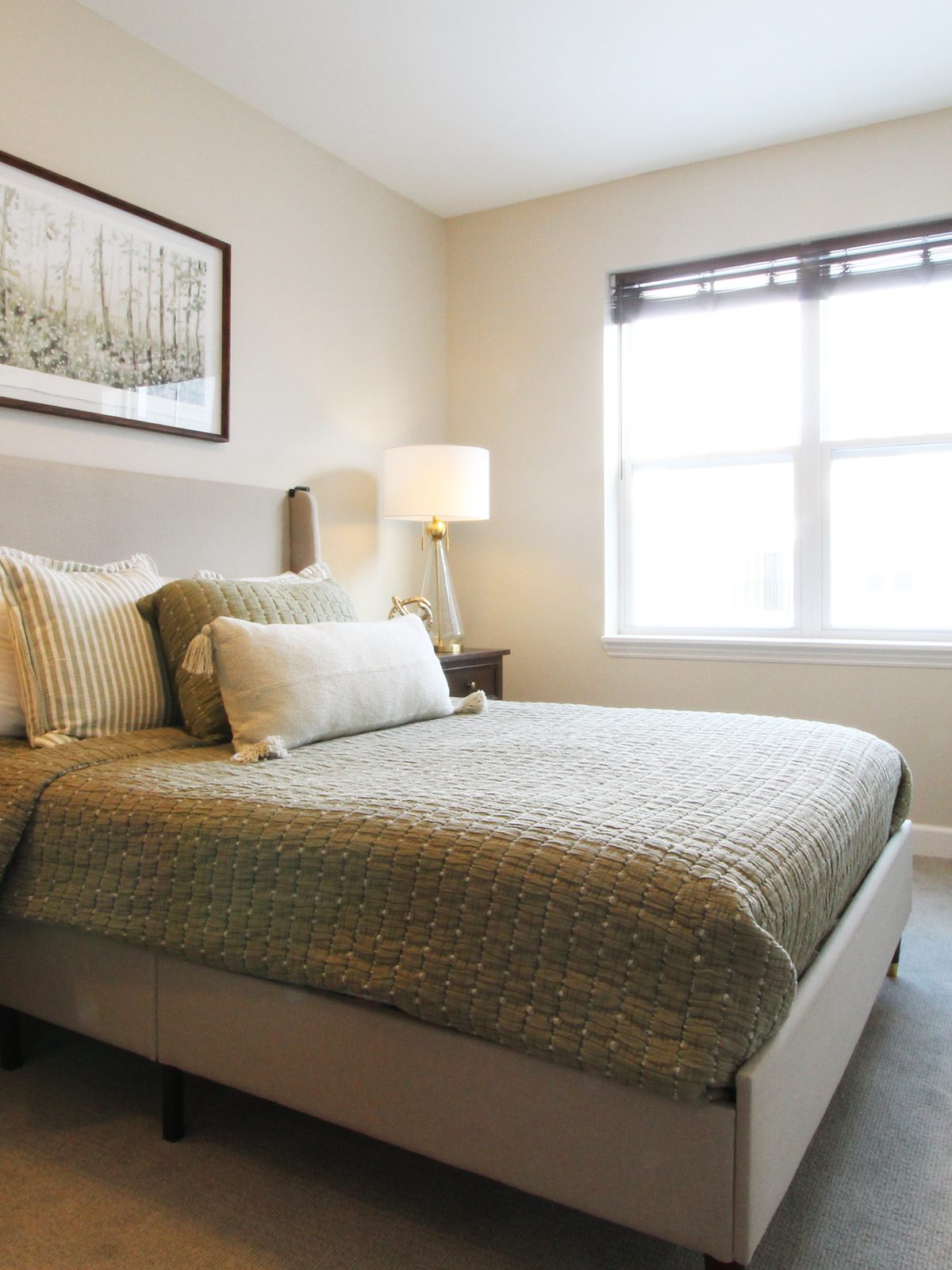 Cozy bedroom with green textured bedding and natural light at Evolve at Lake Zurich